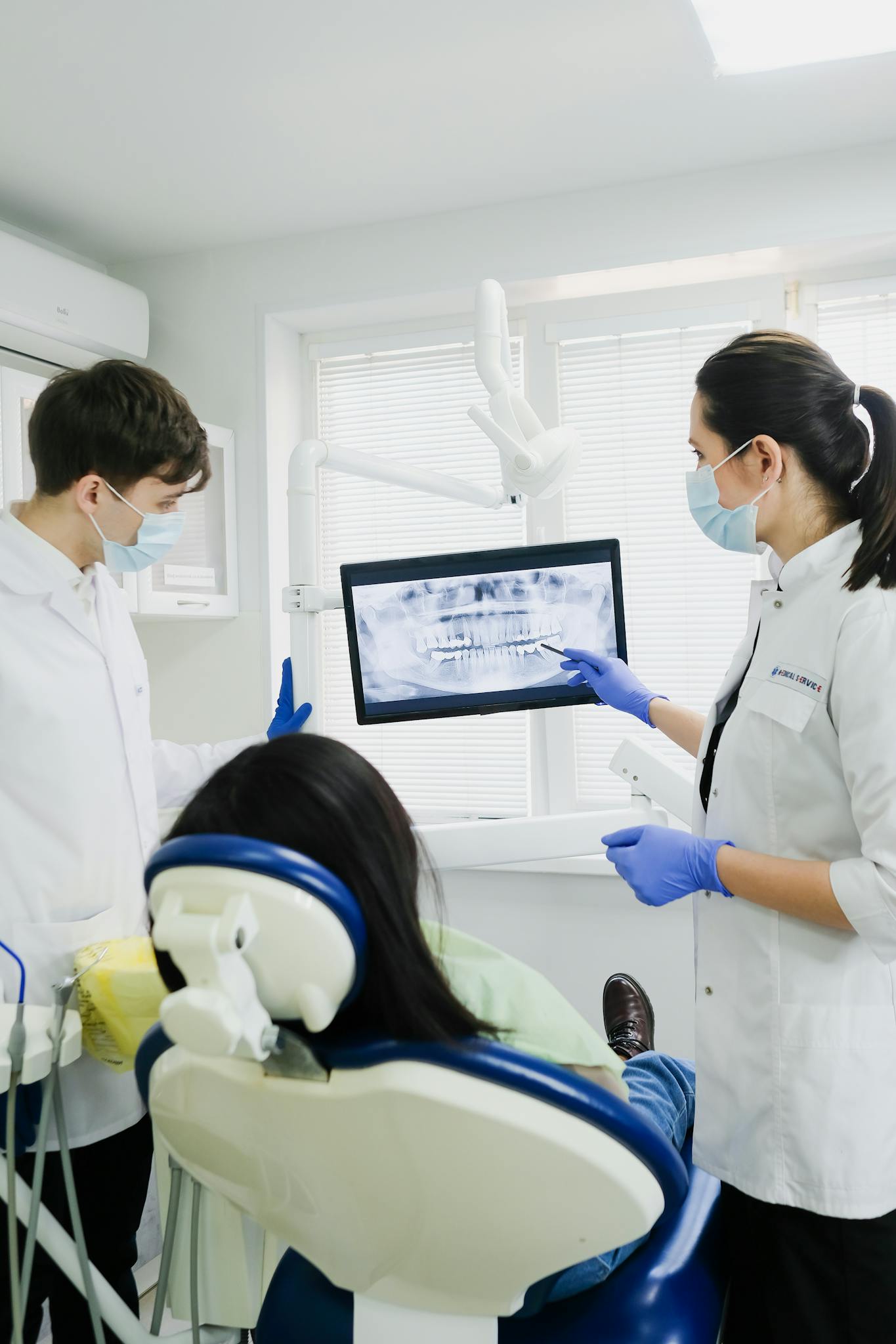 Dentists examining a patient's dental x-ray in a modern clinic setting.
